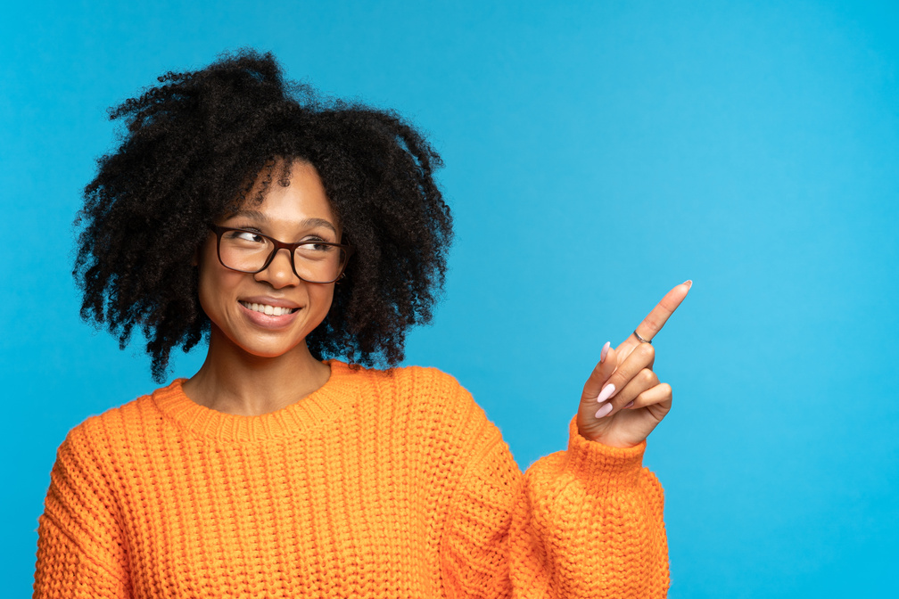 Smiling Mix Race Woman in Glasses Point Finger to Empty Space for Product, Online Courses or Service